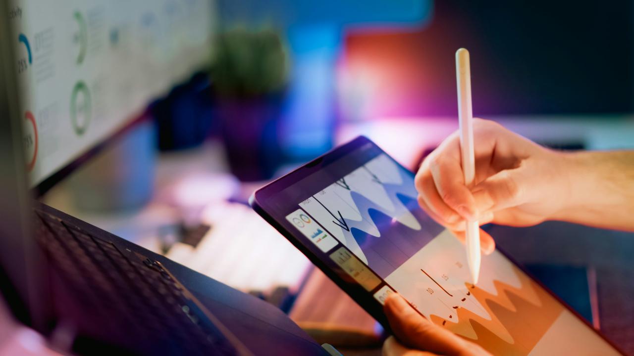 Orang yang menggunakan stylus pada tablet dengan grafik.