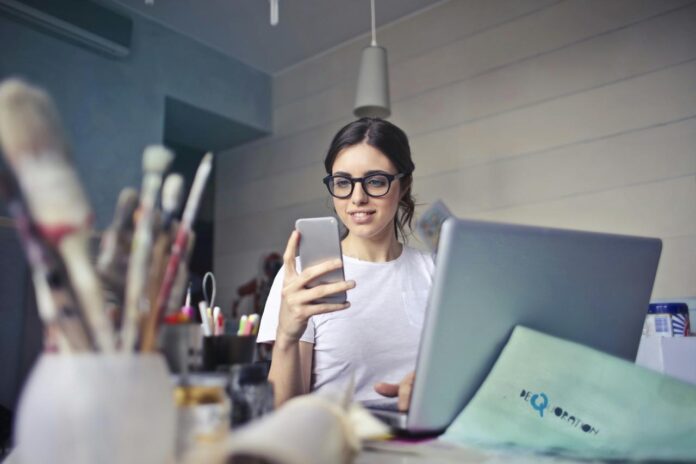 Wanita berbaju putih menggunakan smartphone