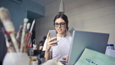 Wanita berbaju putih menggunakan smartphone