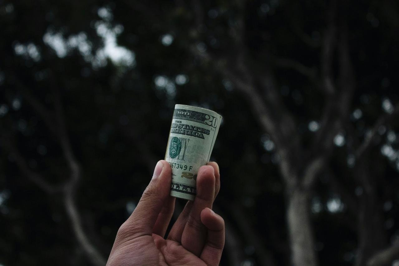 orang yang memegang uang kertas dolar AS